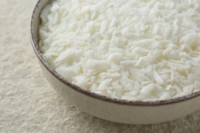 Soy wax in bowl on white textured table, closeup