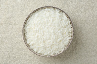 Soy wax in bowl on white textured table, top view