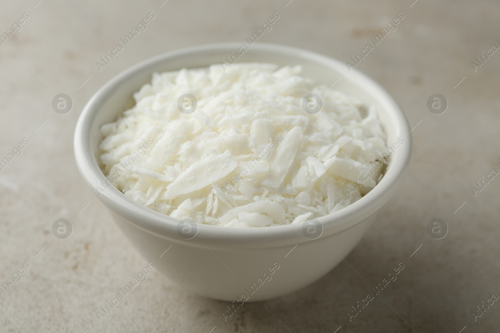 Photo of Soy wax in bowl on light grey table, closeup