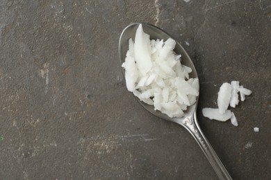 Photo of Soy wax in spoon on grey table, top view