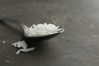 Soy wax in spoon on grey table, closeup. Space for text