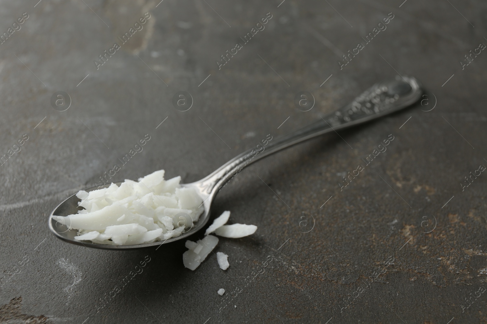 Photo of Soy wax in spoon on grey table