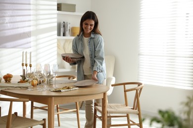 Woman setting table for dinner at home