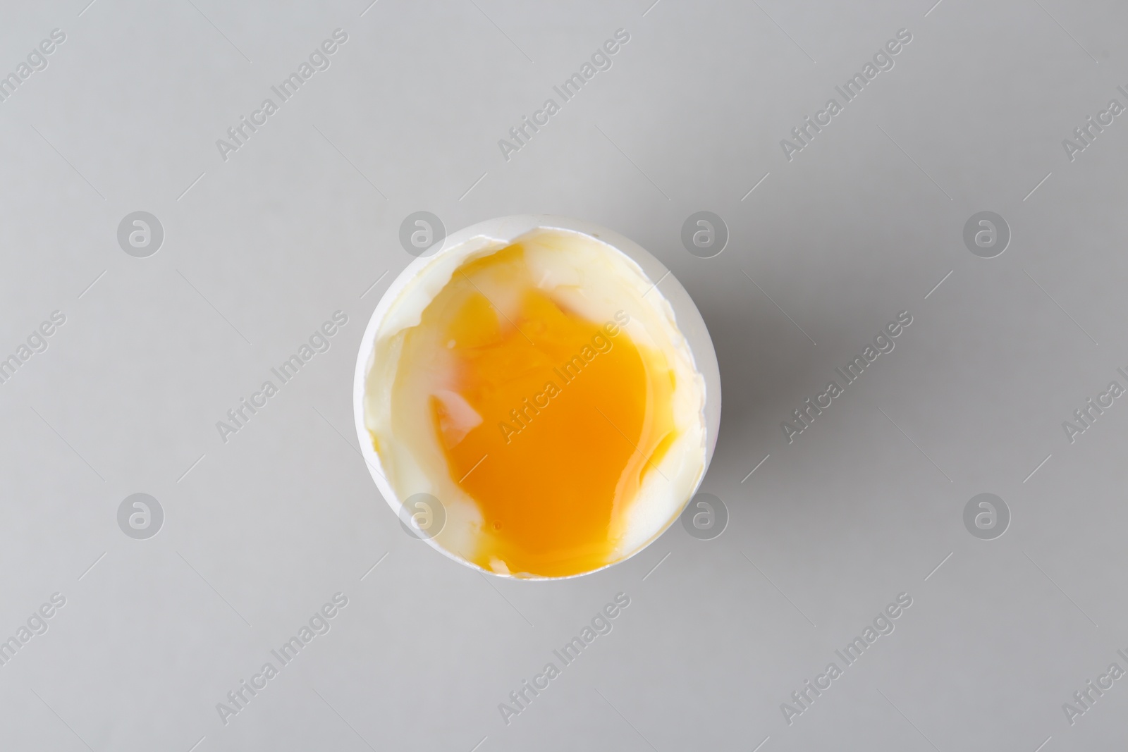 Photo of Soft boiled egg in cup on light grey background, top view