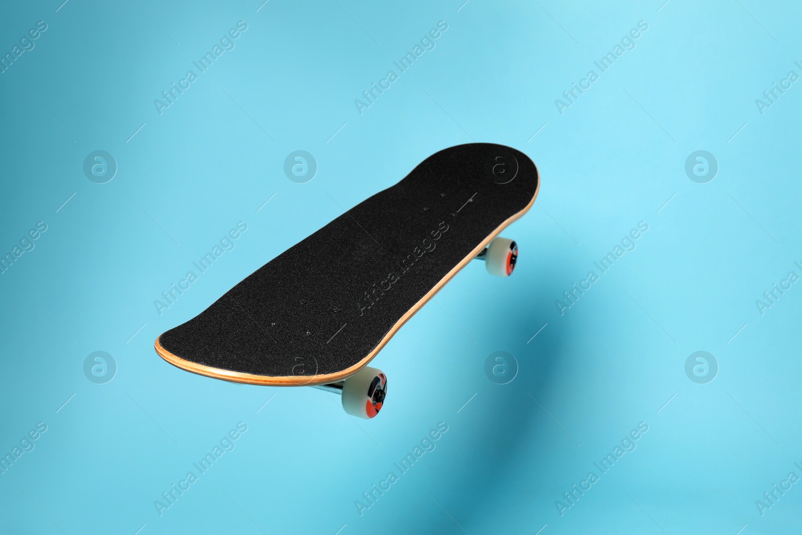 Photo of One skateboard on light blue background, space for text. Sports equipment