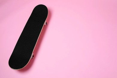 Photo of One skateboard on pink background, space for text