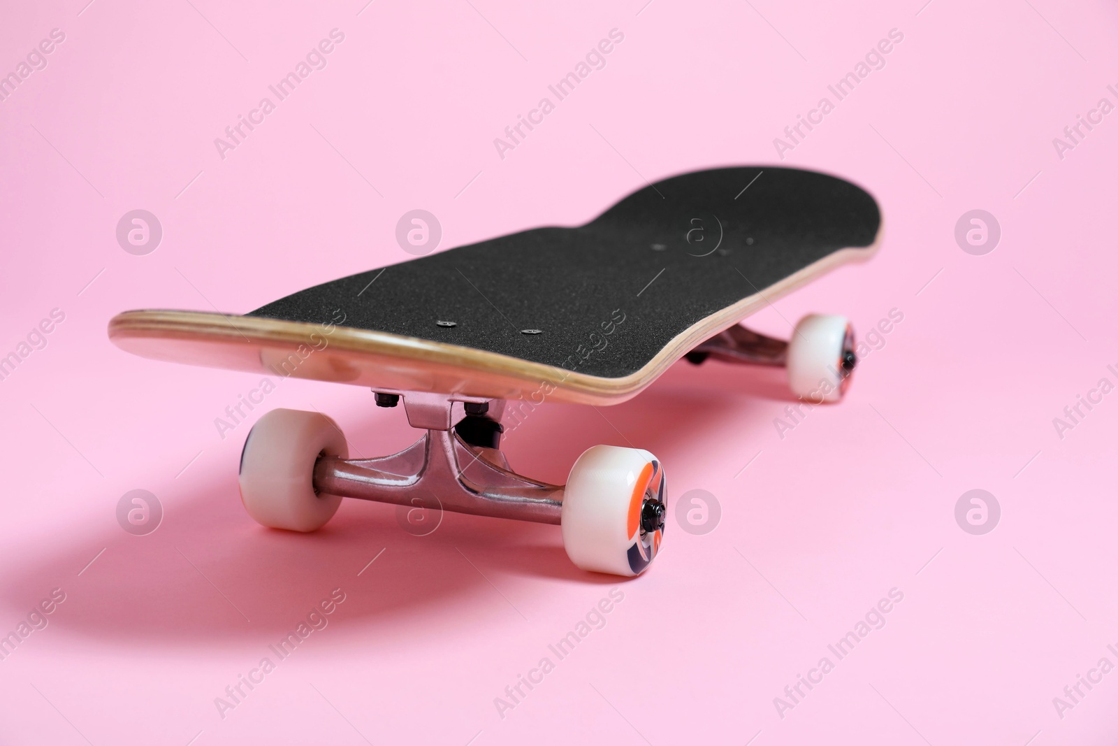 Photo of One skateboard on pink background, closeup. Sports equipment