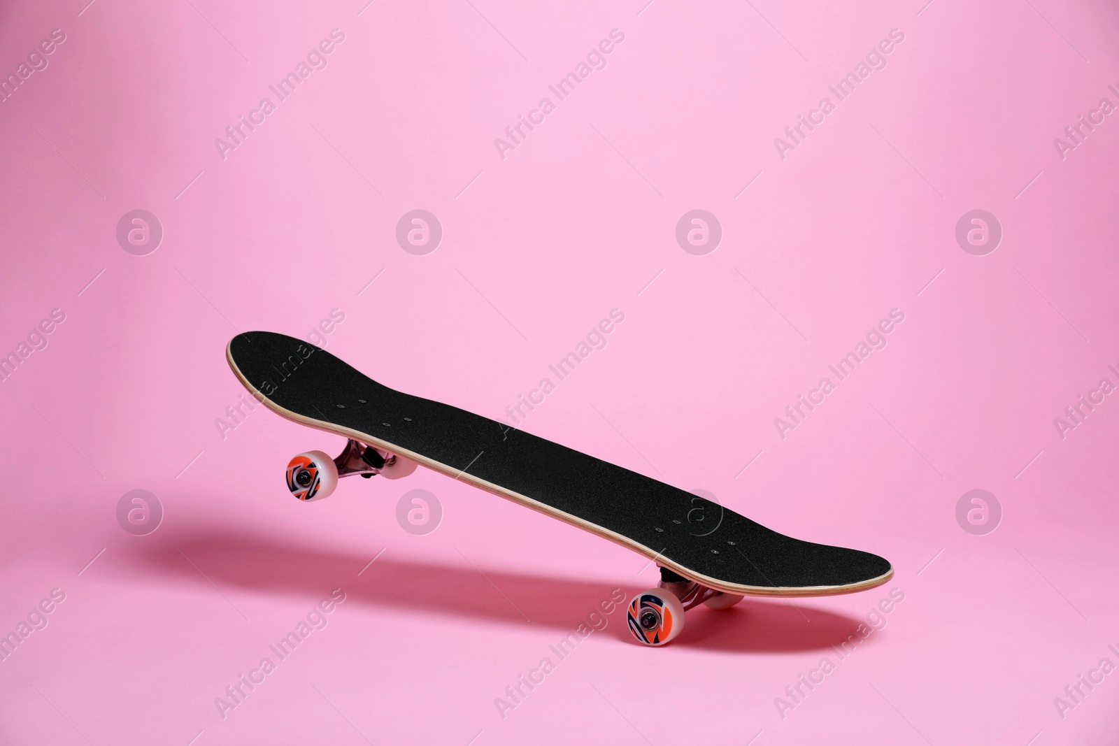 Photo of One skateboard on pink background. Sports equipment