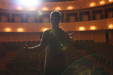 Photo of Professional actor rehearsing on stage in theatre, back view