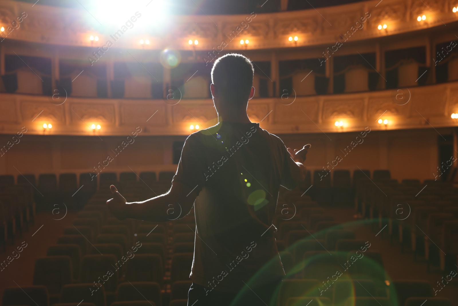 Photo of Professional actor rehearsing on stage in theatre, back view