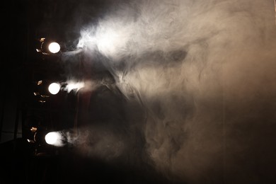 Photo of Professional spotlights and smoke on stage in theatre