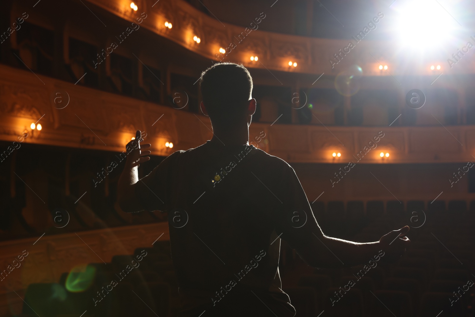 Photo of Professional actor rehearsing on stage in theatre, back view