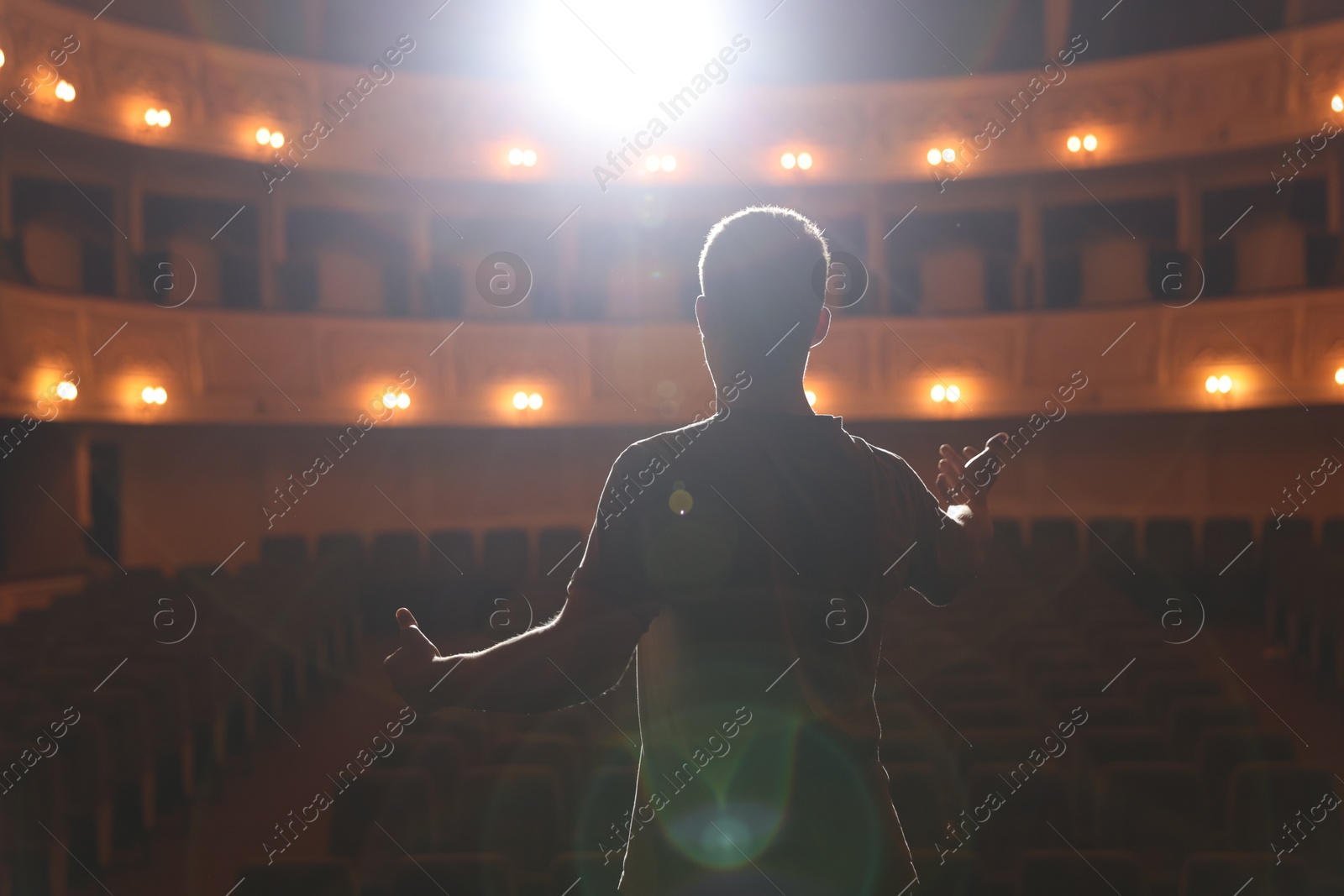 Photo of Professional actor rehearsing on stage in theatre, back view