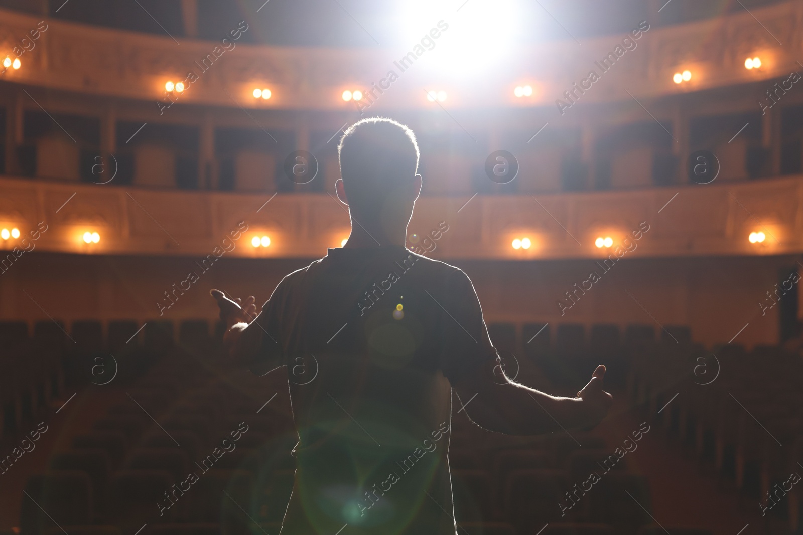 Photo of Professional actor rehearsing on stage in theatre, back view