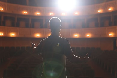 Photo of Professional actor rehearsing on stage in theatre, back view