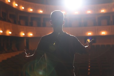 Photo of Professional actor rehearsing on stage in theatre, back view