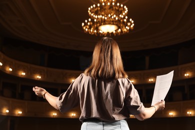 Photo of Professional actress rehearsing on stage in theatre, back view