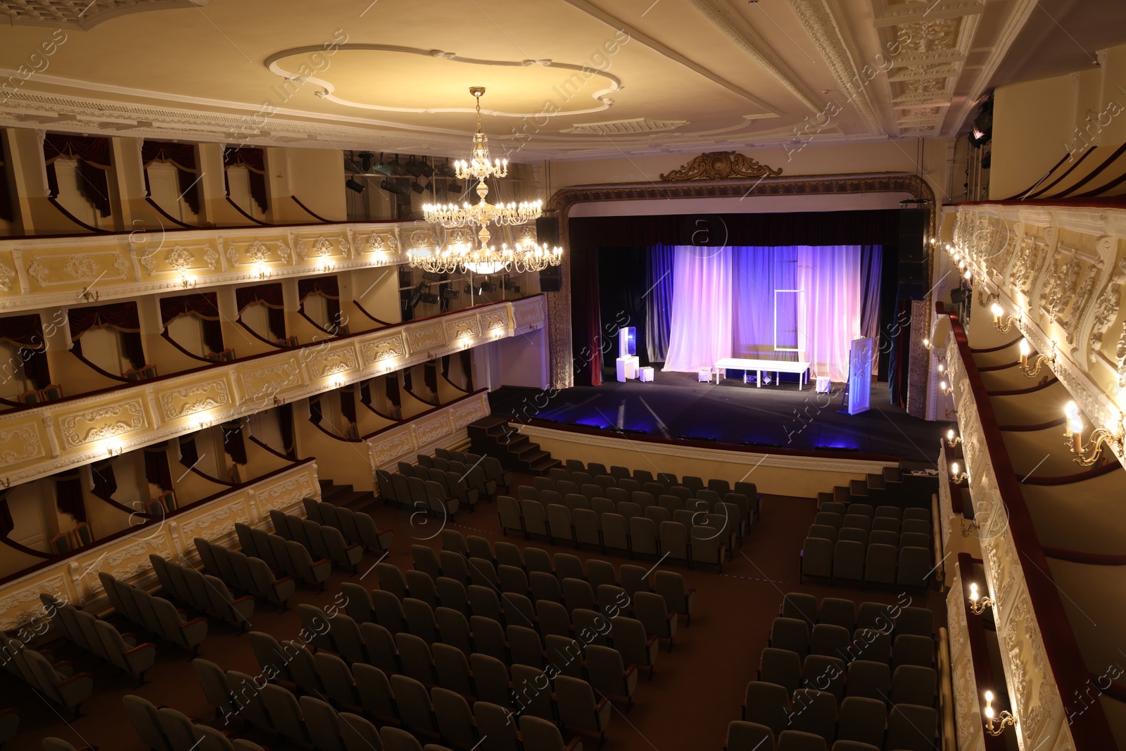 Photo of Theatre interior with stage, rows of comfortable seats and beautiful chandelier