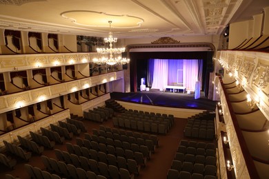 Photo of Theatre interior with stage, rows of comfortable seats and beautiful chandelier