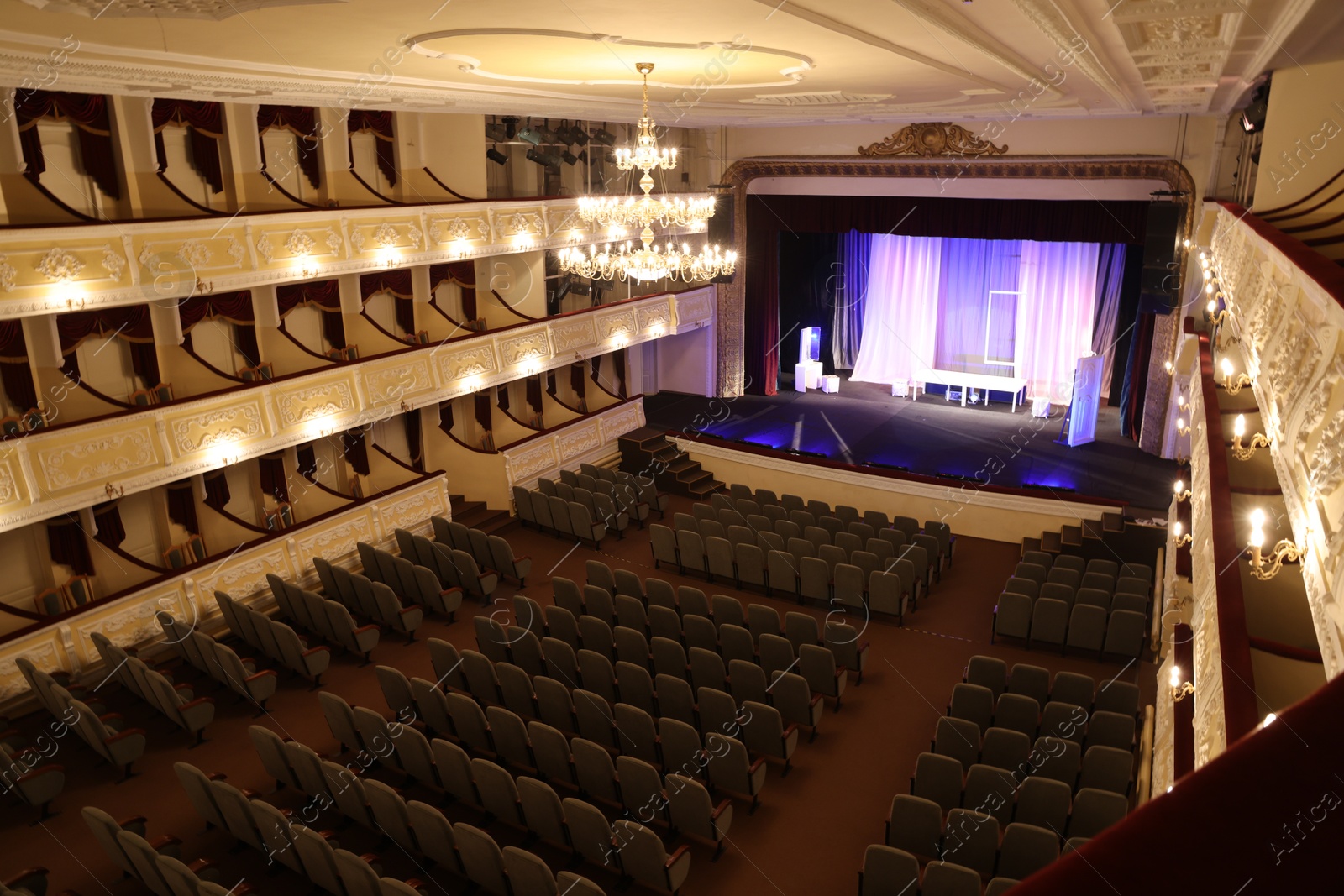 Photo of Theatre interior with stage, rows of comfortable seats and beautiful chandelier