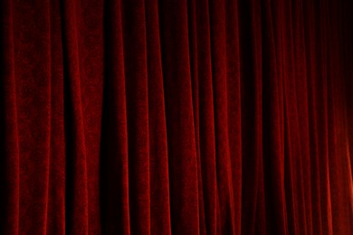 Photo of Elegant red curtains in theatre as background, closeup