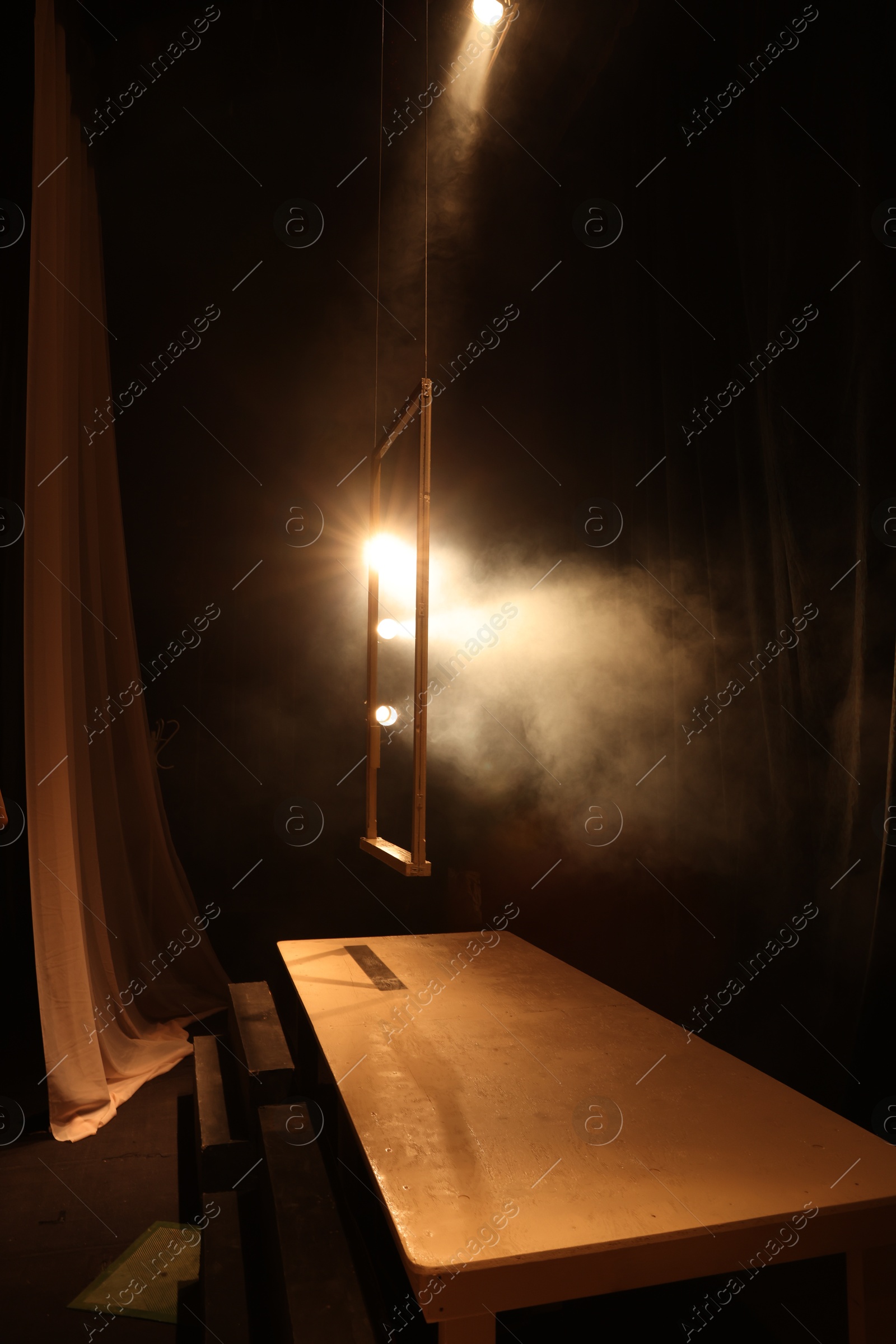 Photo of Wooden frame, table and professional spotlights on stage in theatre