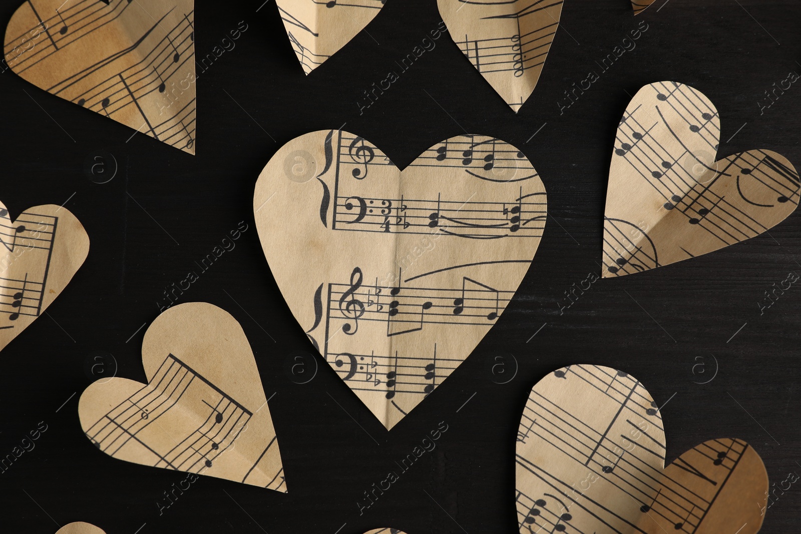 Photo of Paper hearts with notes on black wooden table, flat lay