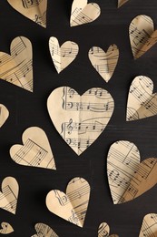 Paper hearts with notes on black wooden table, flat lay