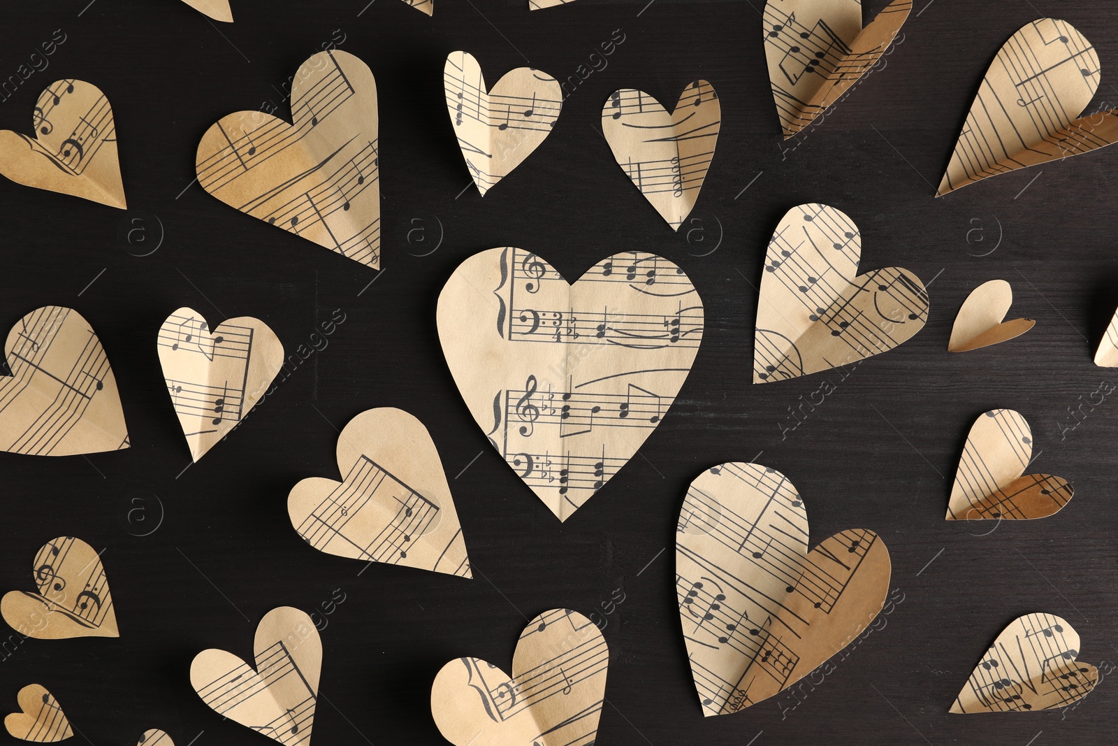 Photo of Paper hearts with notes on black wooden table, flat lay