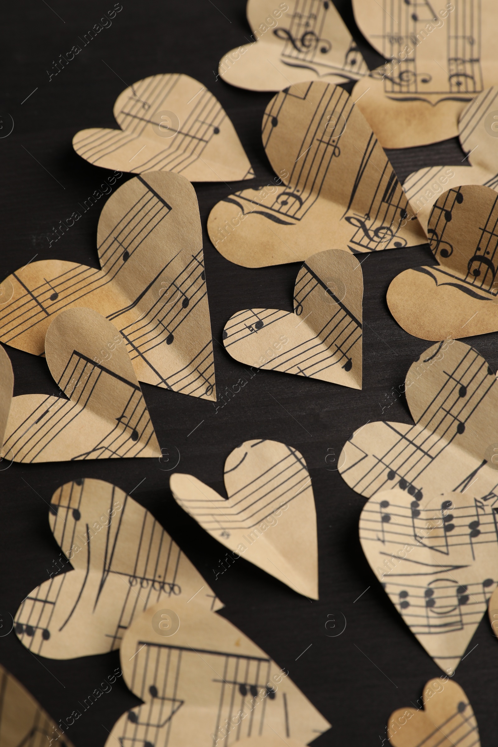 Photo of Paper hearts with notes on black wooden table, closeup