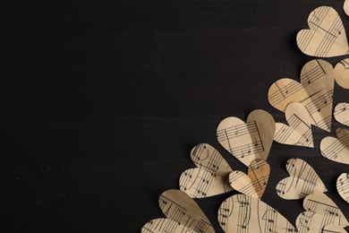 Photo of Paper hearts with notes on black wooden table, flat lay. Space for text