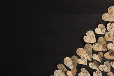 Paper hearts with notes on black wooden table, flat lay. Space for text