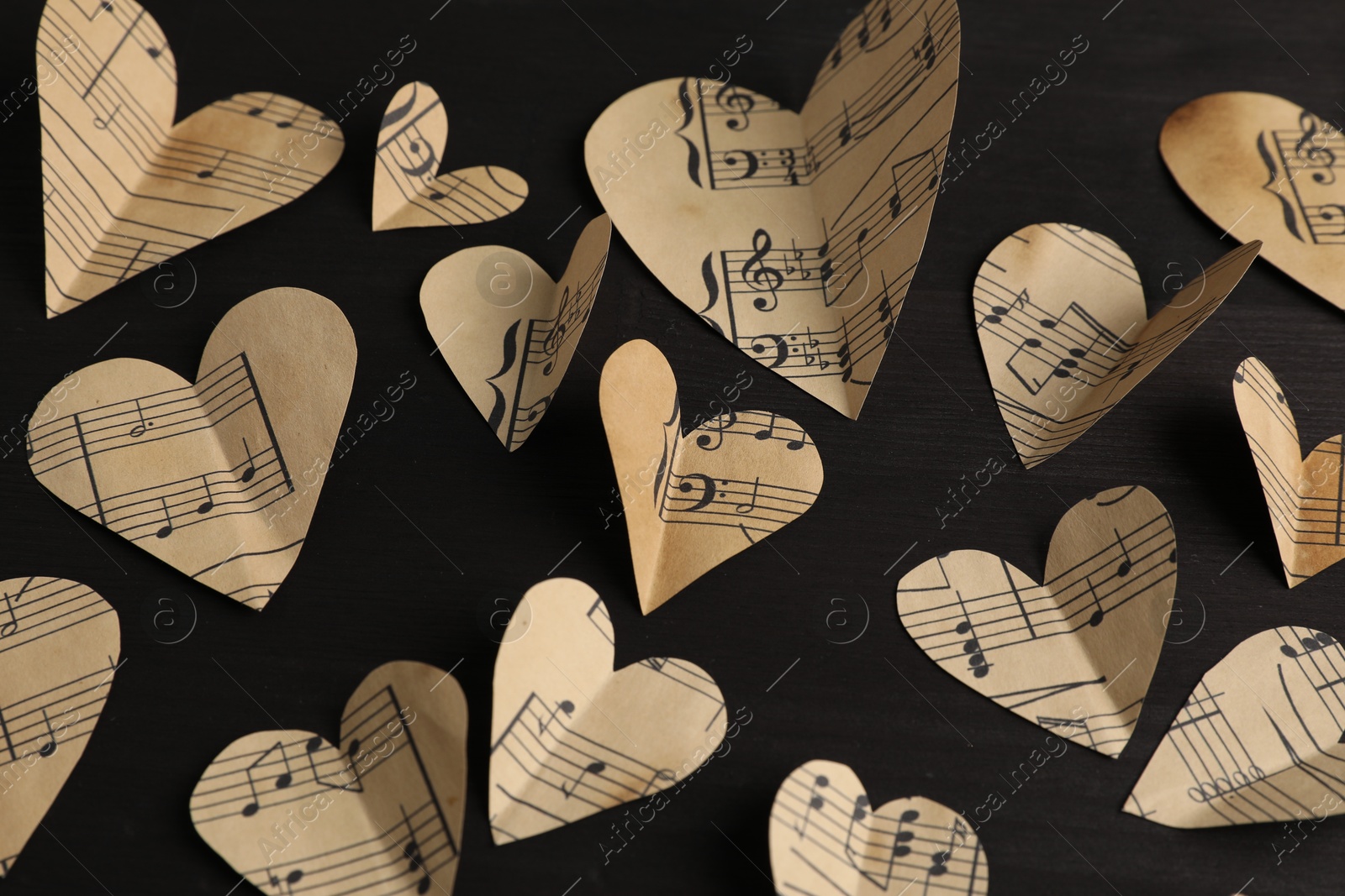 Photo of Paper hearts with notes on black wooden table, above view