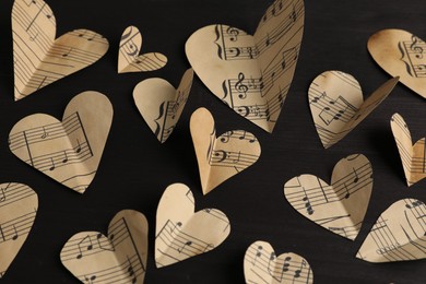 Photo of Paper hearts with notes on black wooden table, above view