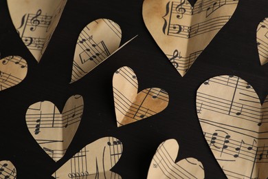 Photo of Paper hearts with notes on black wooden table, flat lay