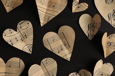 Photo of Paper hearts with notes on black wooden table, flat lay