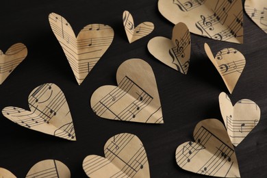 Photo of Paper hearts with notes on black wooden table, closeup