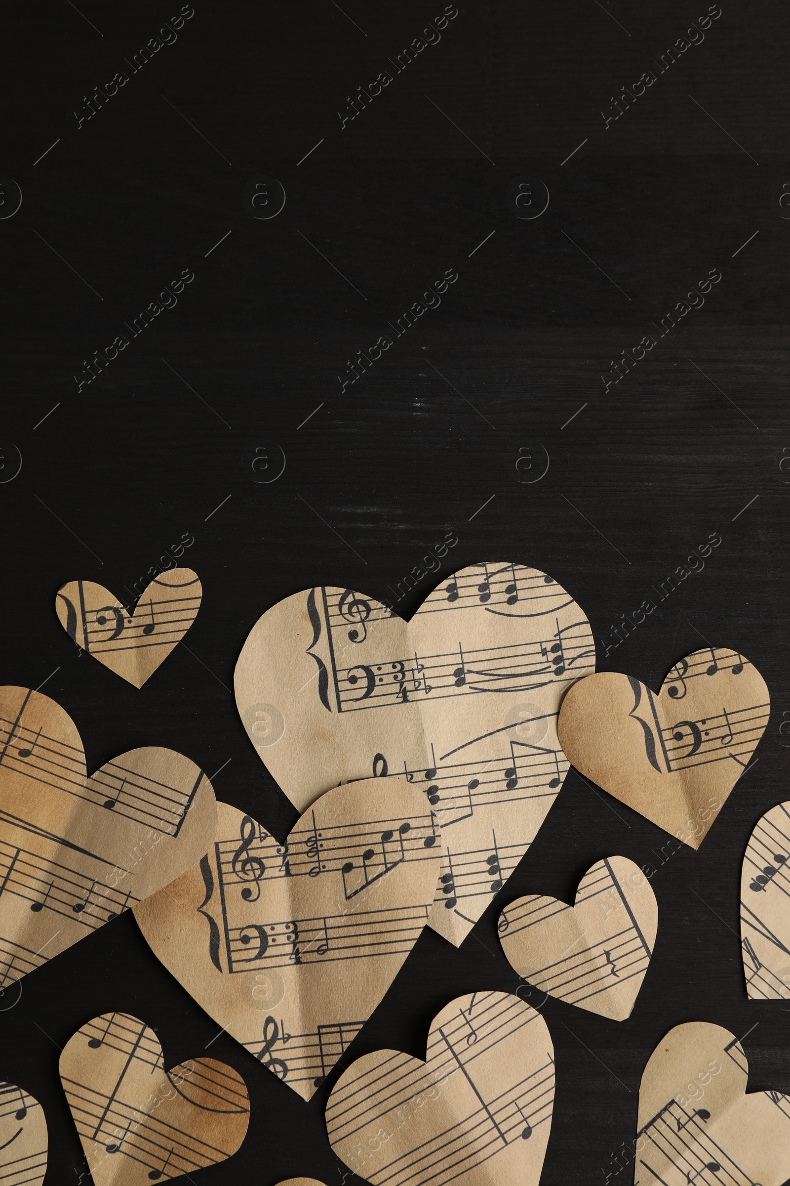 Photo of Paper hearts with notes on black wooden table, flat lay. Space for text