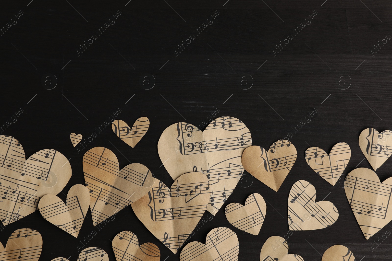 Photo of Paper hearts with notes on black wooden table, flat lay. Space for text