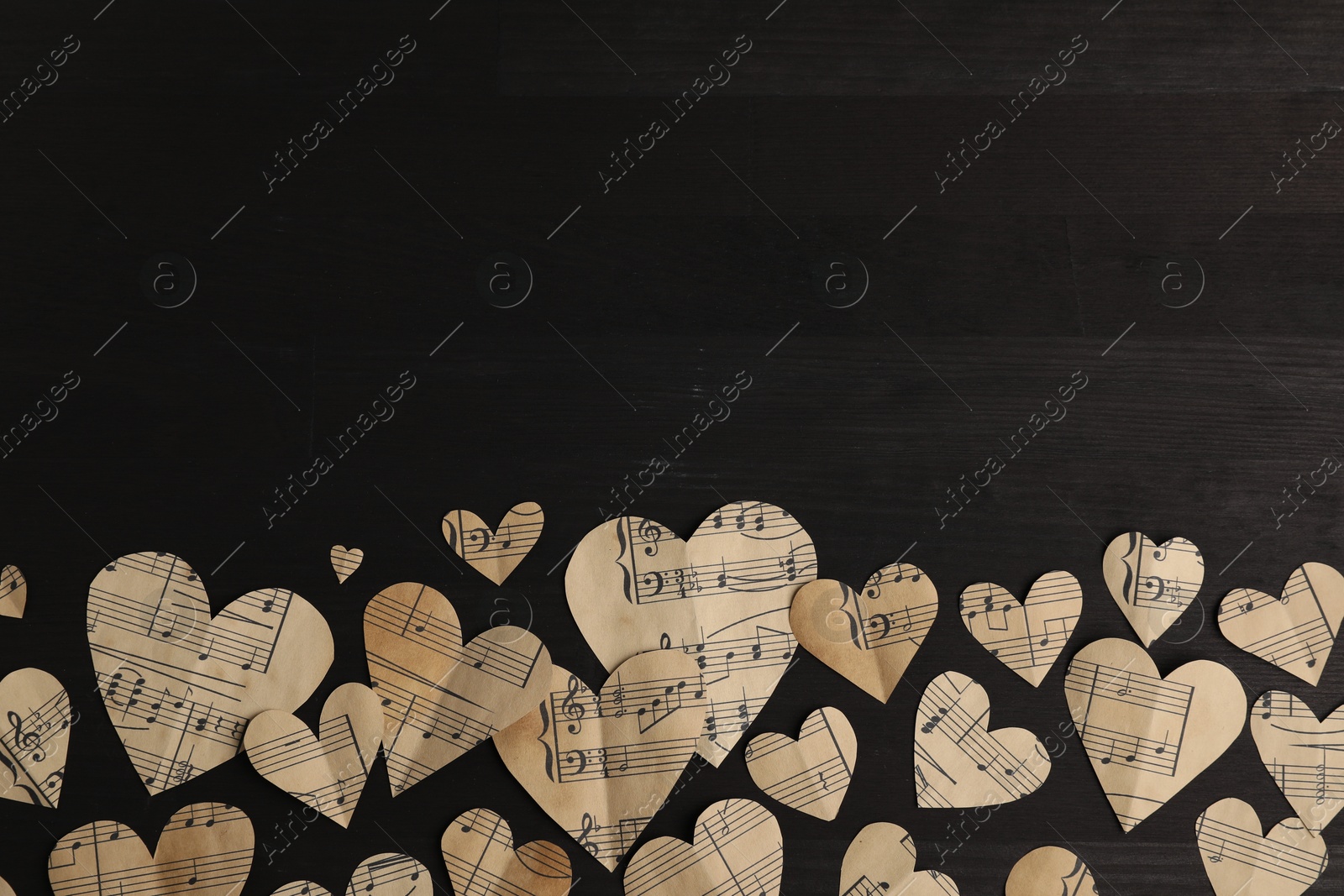 Photo of Paper hearts with notes on black wooden table, flat lay. Space for text