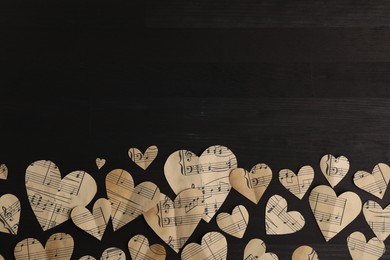 Paper hearts with notes on black wooden table, flat lay. Space for text