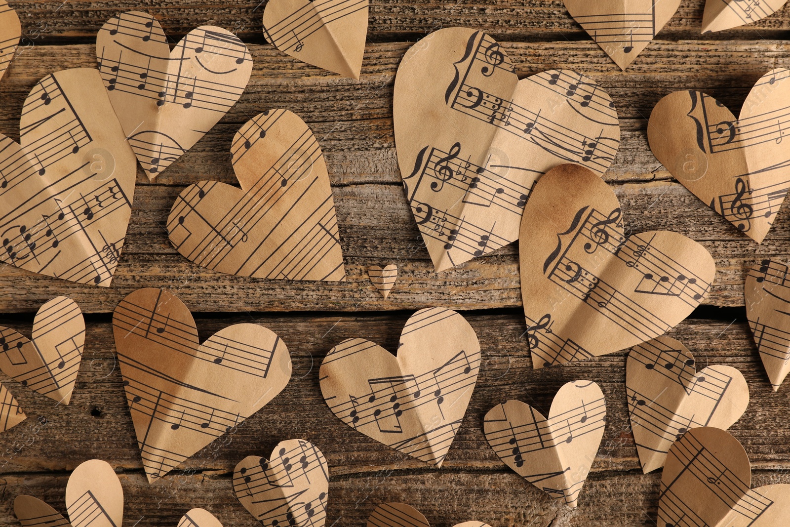 Photo of Paper hearts with notes on wooden table, flat lay