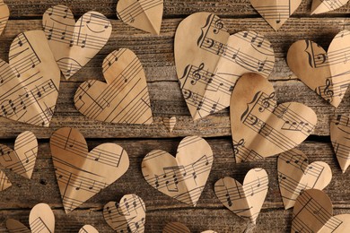 Paper hearts with notes on wooden table, flat lay