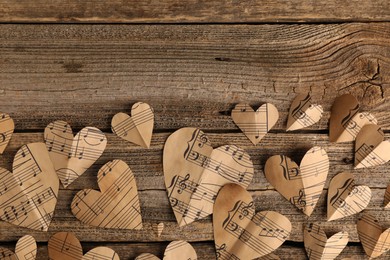 Photo of Paper hearts with notes on wooden table, flat lay. Space for text