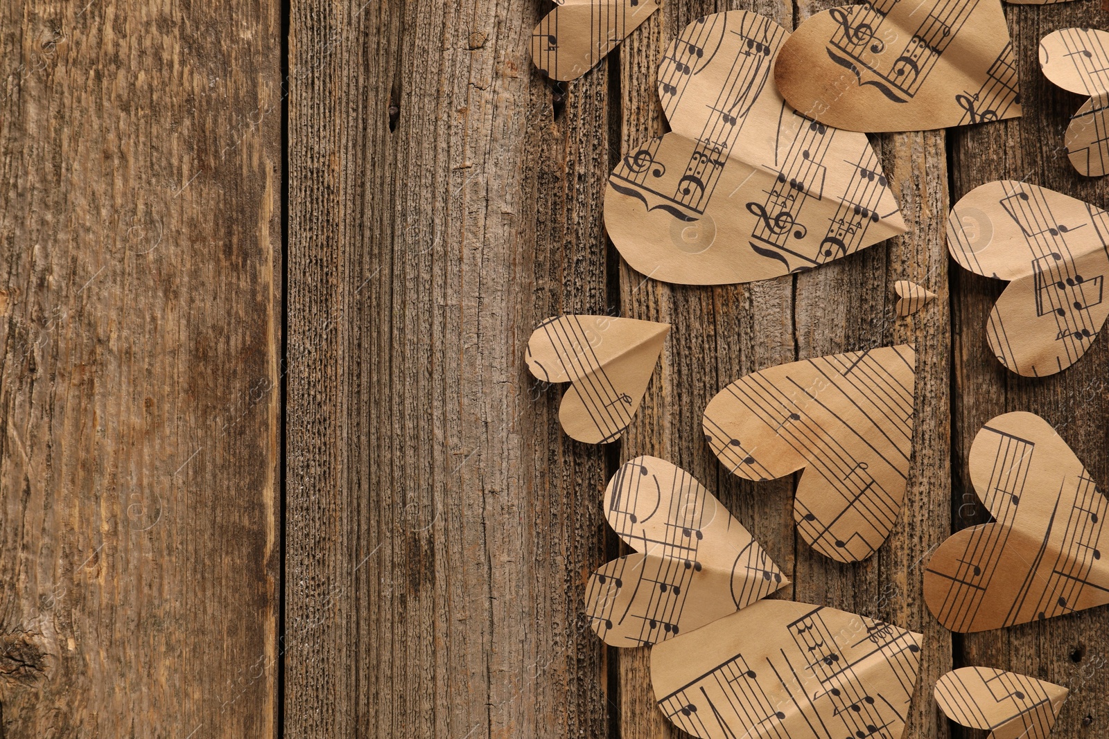 Photo of Paper hearts with notes on wooden table, flat lay. Space for text