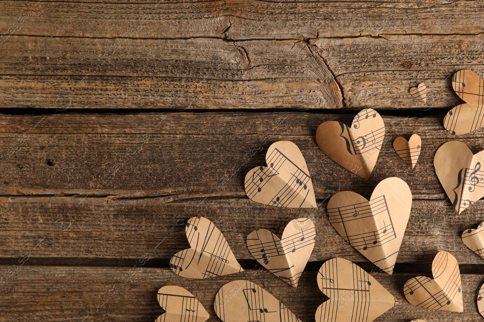 Photo of Paper hearts with notes on wooden table, flat lay. Space for text