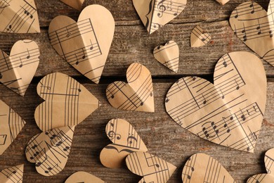 Photo of Paper hearts with notes on wooden table, flat lay