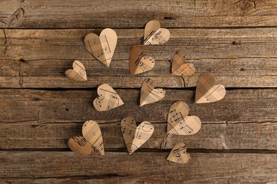 Paper hearts with notes on wooden table, flat lay