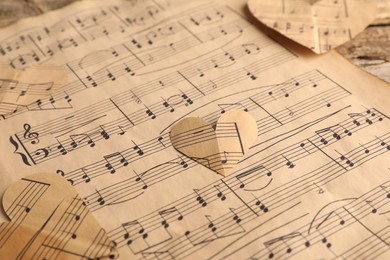 Photo of Paper hearts with notes and musical note sheet on table, closeup