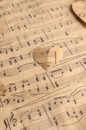 Paper hearts with notes on musical note sheet, closeup